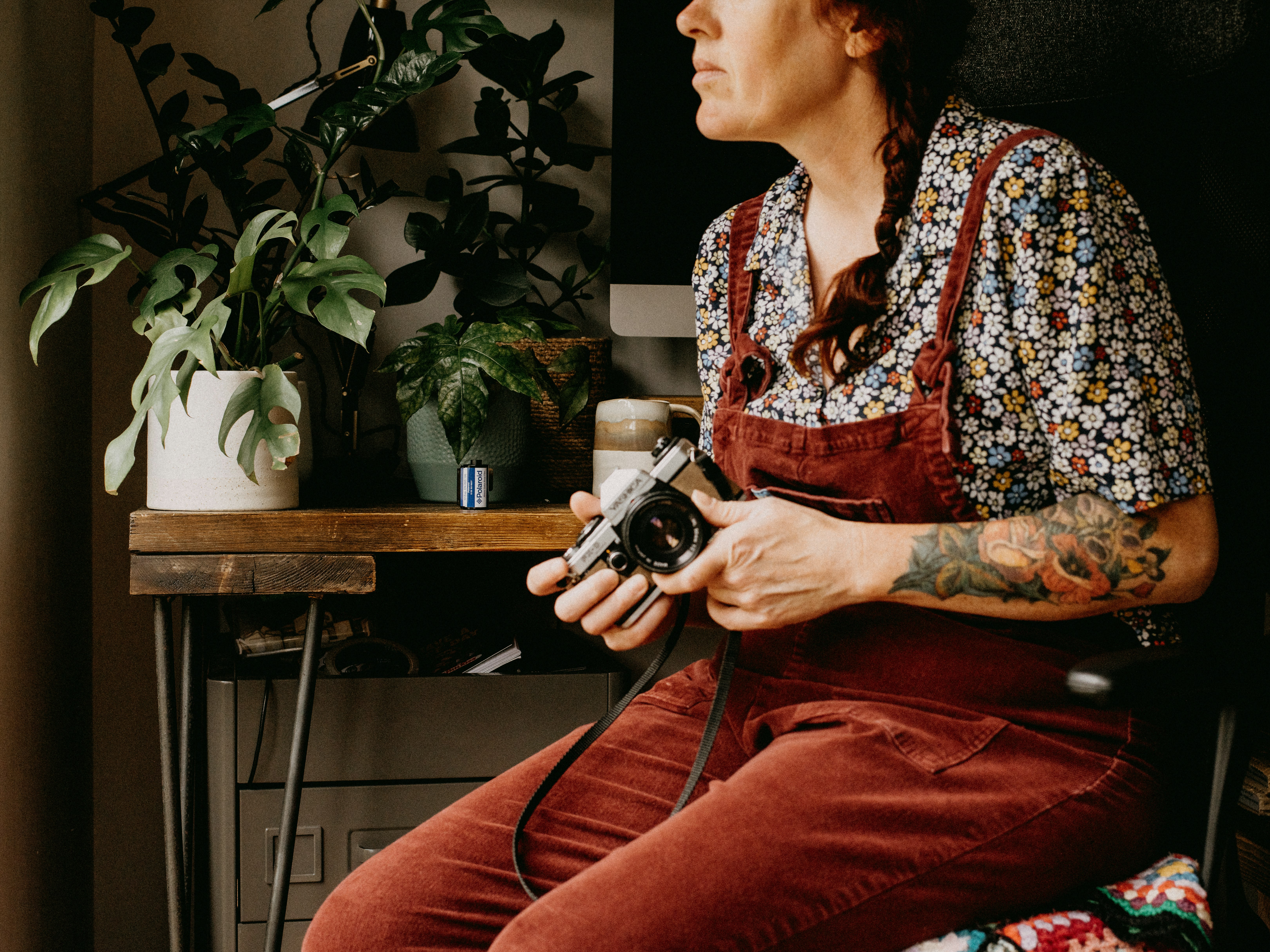 man in black and white floral dress shirt and red pants holding black and silver dslr